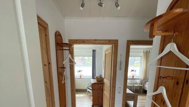 A hallway with wooden doors, a tiled floor, and a ceiling light fixture. - Strandläufer (Wangerland)