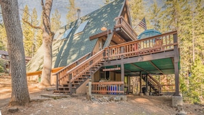 Een blokhut met een houten trap, een overdekte veranda en een bordje met de tekst 'Old Canyon Bear Cabin'.