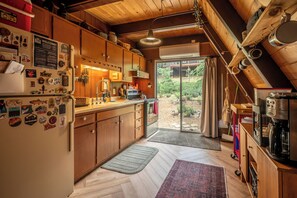 A kitchen with wooden cabinets, a refrigerator, a stove, and a coffee maker.