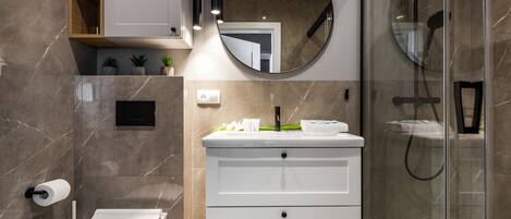 A modern bathroom with a toilet, vanity, and glass shower enclosure.