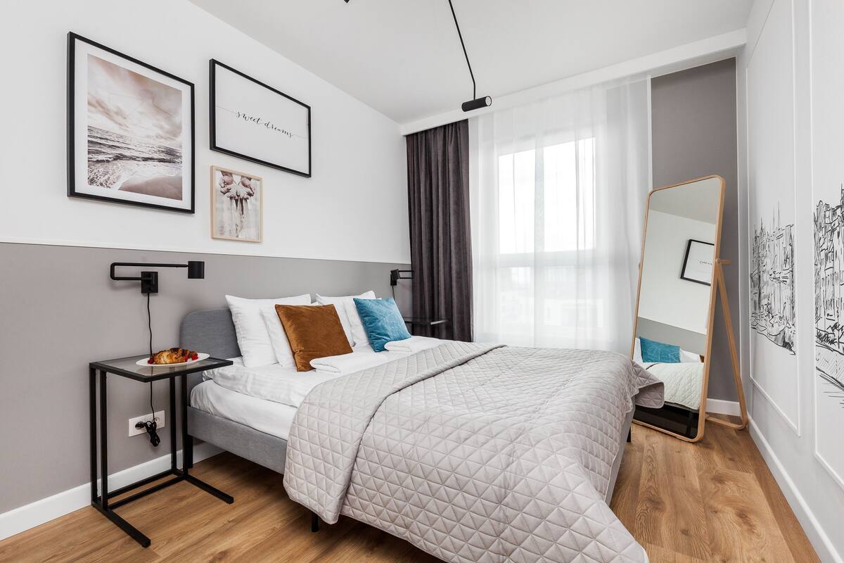 Un dormitorio moderno con una cama, una mesita de noche y un espejo grande.