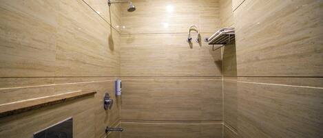 A small, modern shower with a handheld showerhead and a wall-mounted faucet.