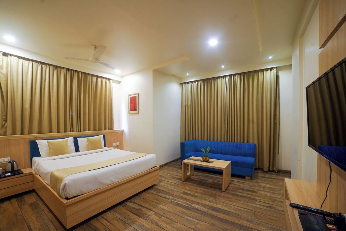 Una camera d'albergo con un letto, un divano blu, un tavolino e una TV.