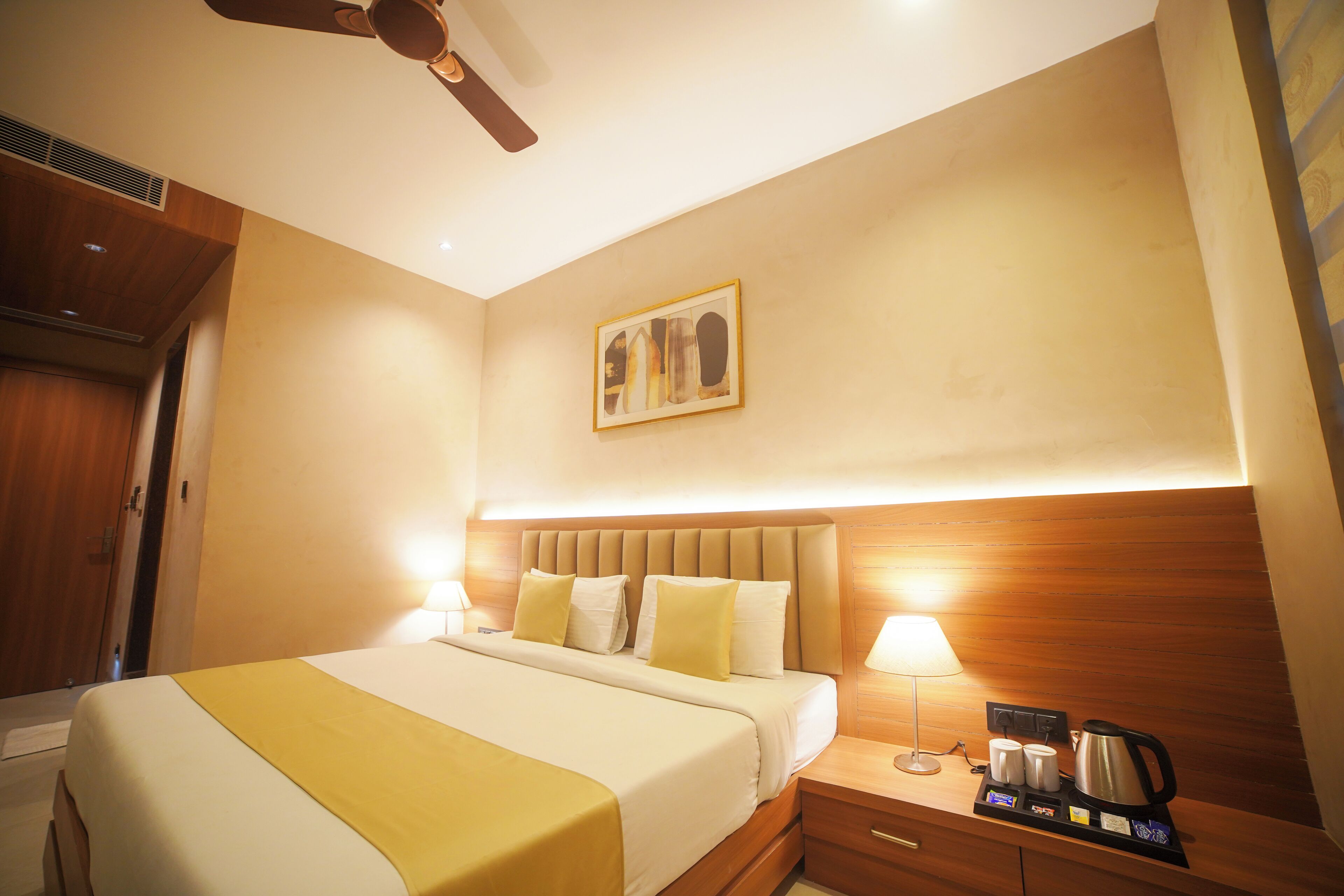 A hotel room with a bed, bedside table, lamp, and a coffee maker.