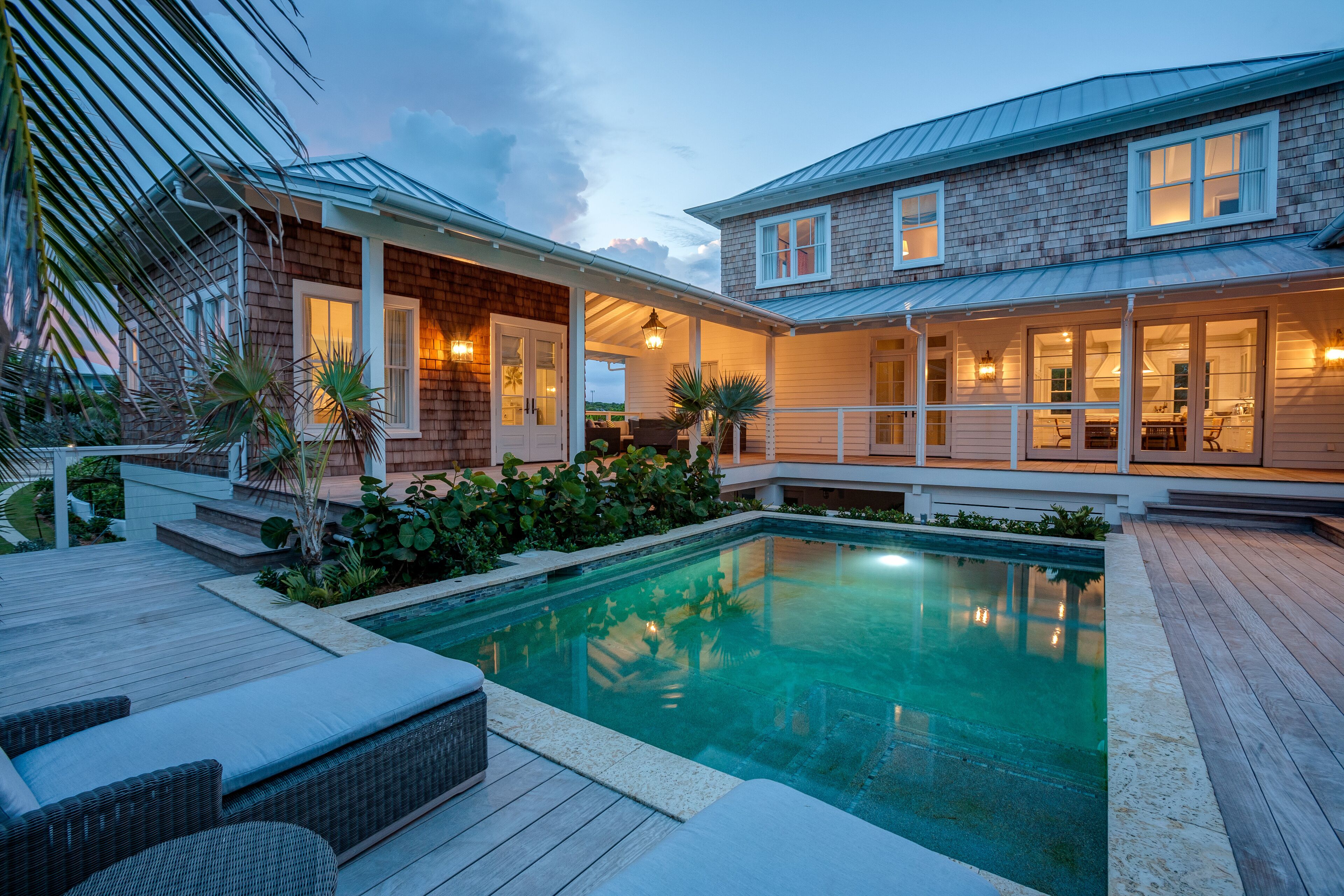 Un espace aménagé au bord de la piscine, avec une terrasse en bois, des sièges d’extérieur et une piscine.