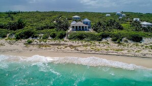 A coastal property with multiple houses, a beach, and lush greenery. - Sea Oats, Hope Town - Luxury Beachfront Home (Hope Town)