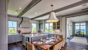 A spacious kitchen with a large island, modern cabinetry, and a dining area set for six. - Sea Oats, Hope Town - Luxury Beachfront Home (Hope Town)