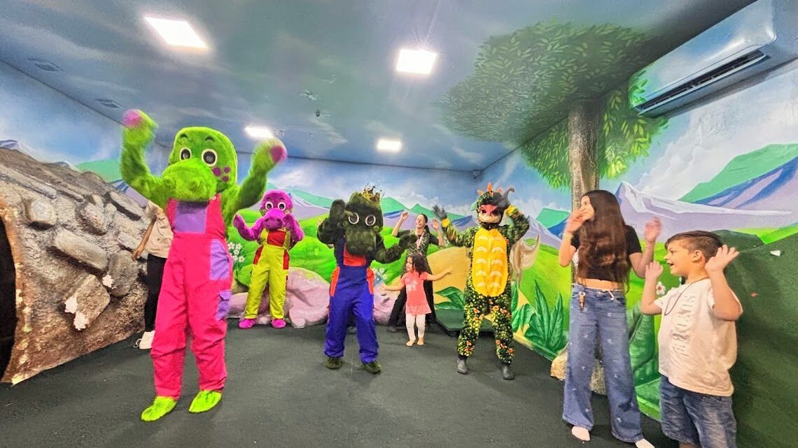 A group of people in colorful costumes in a room with a mural of a landscape.