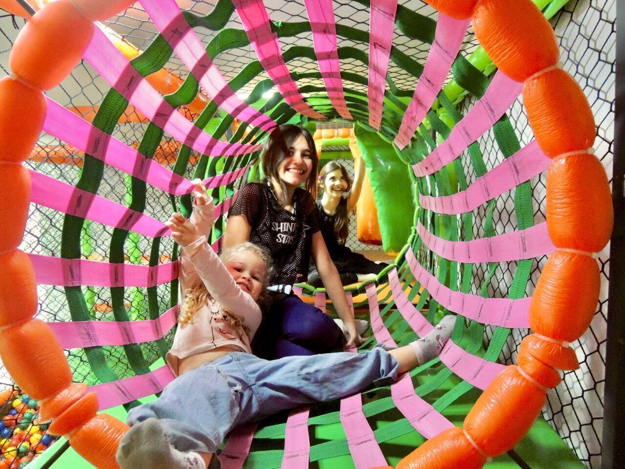 A play area with a netted tunnel and inflatable structures.