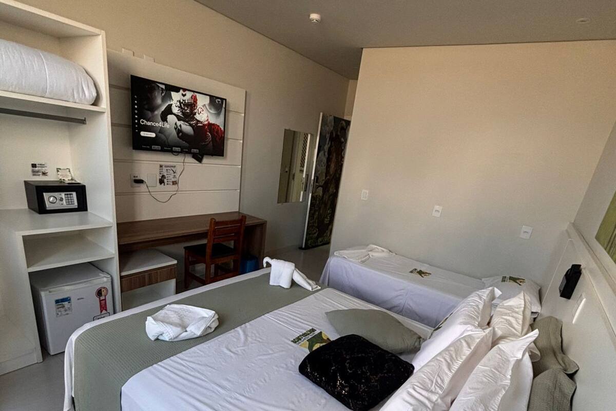 Habitación de hotel con una cama grande, un escritorio, un televisor y un refrigerador pequeño.