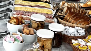 Una mesa de bufé con diversos alimentos, incluyendo pasteles, bollos y sándwiches.