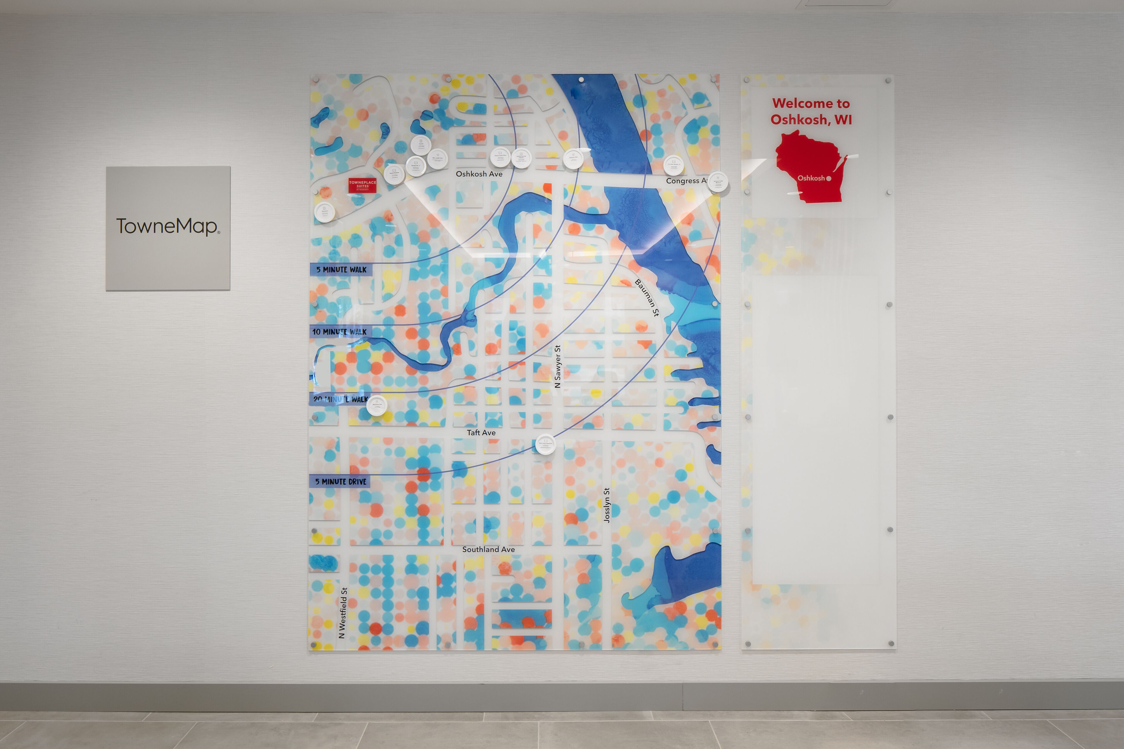 A wall-mounted map with street names and a welcome sign for Oshkosh, WI.