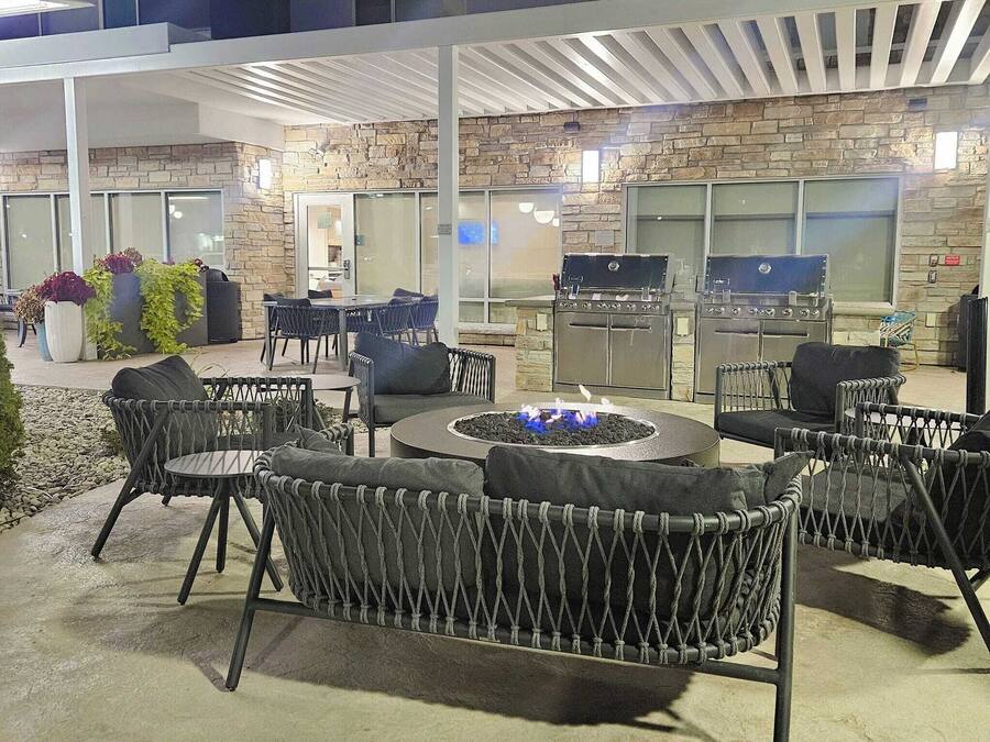 An outdoor patio area with seating, a fire pit, and barbecue grills.