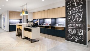 Une cuisine moderne avec des meubles en bois, un îlot central doté de tabourets de bar et un tableau noir sur lequel est écrit un message motivant.