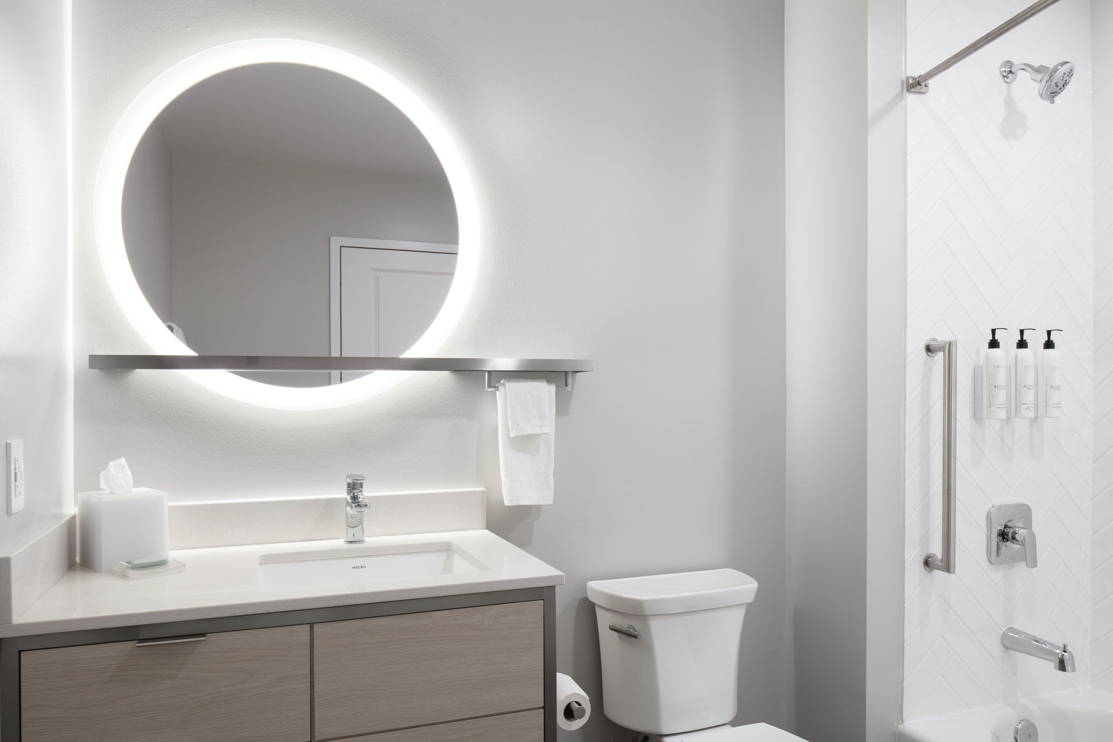 A modern bathroom with a round mirror, a toilet, and a shower area.