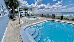A pool area with two separate pools, a covered seating area, and a view of the ocean. - Beach-Front Condo, 2 Reserved Parking Spaces!, Large Balcony, Fabulous Views! (Panama City Beach)