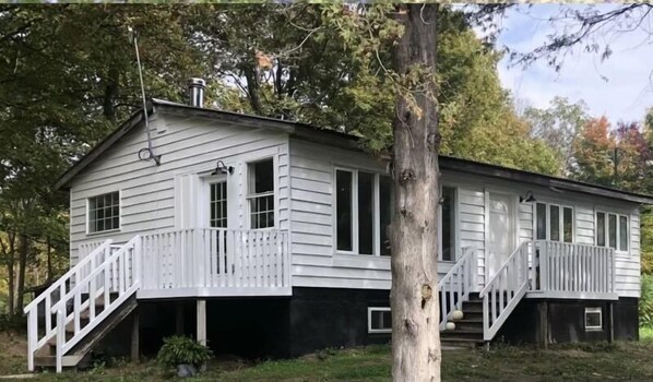 Et toetagers hus med hvide facadebrædder, en veranda med hvide gelændere, og en trappe op til anden etage.