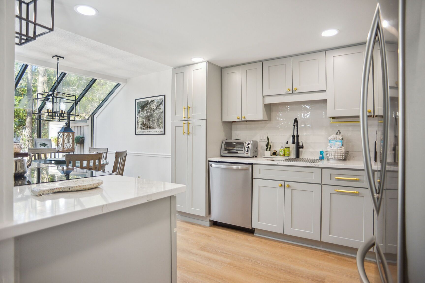 A modern kitchen with white cabinets, a built-in dishwasher, and a large island with a glass top.