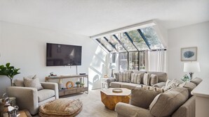 A modern living room with a sofa set, a coffee table, and a TV mounted on the wall.