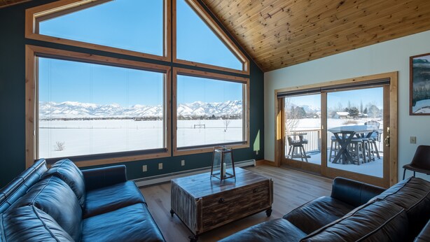 A spacious living room with large windows, a wooden ceiling, and a view of mountains. - Mountain View Home w/Hot Tub - Close to Downtown! (Bozeman)