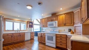 A spacious kitchen with wooden cabinets, a microwave, stove, and a dishwasher. - Mountain View Home w/Hot Tub - Close to Downtown! (Bozeman)