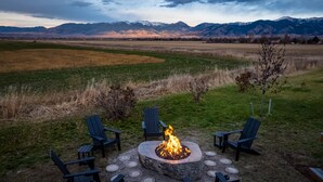 A fire pit with chairs around it, set in a grassy area with mountains in the background. - Mountain View Home w/Hot Tub - Close to Downtown! (Bozeman)
