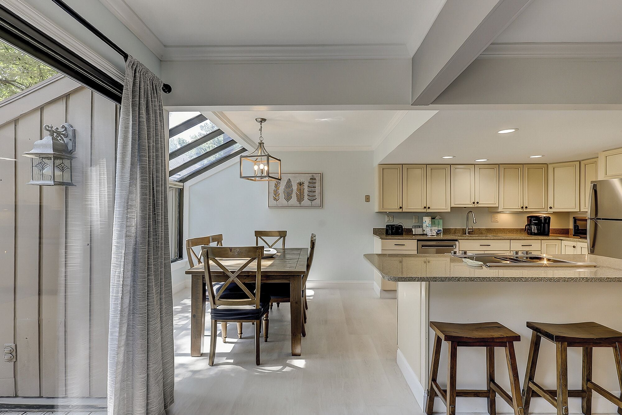 A modern kitchen with wooden cabinets, a central island, and a dining area with a table and chairs.