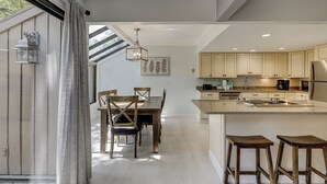 Eine moderne Küche mit Holzschr änken, einer zentralen Kochinsel und einem Essbereich mit Tisch und Stühlen.