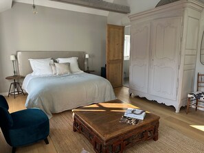 Een slaapkamer met een bed, nachtkastjes, een stoel, een houten salontafel en een kledingkast.