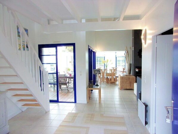 A spacious living area with a staircase, a dining set, and a kitchen area.