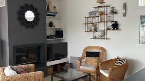 Un salon avec des meubles en osier, une cheminée et des étagères décoratives.