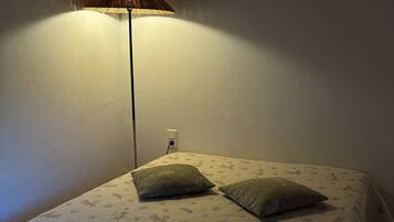 Un lit recouvert d’une couvre-lit à motifs floraux, avec deux oreillers et une serviette blanche pliée.