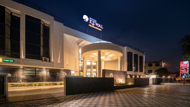 L’entrée d’un hôtel, avec une grande enseigne lumineuse, un espace d’attente abrité et une pancarte indiquant « végétarien uniquement ».