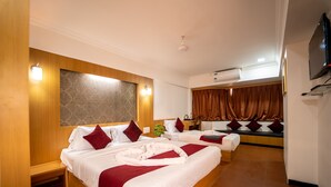 Une chambre d’hôtel avec deux lits, chacun recouvert d’une couverture rouge et blanche, un téléviseur à écran plat fixé au mur et un appareil de climatisation.