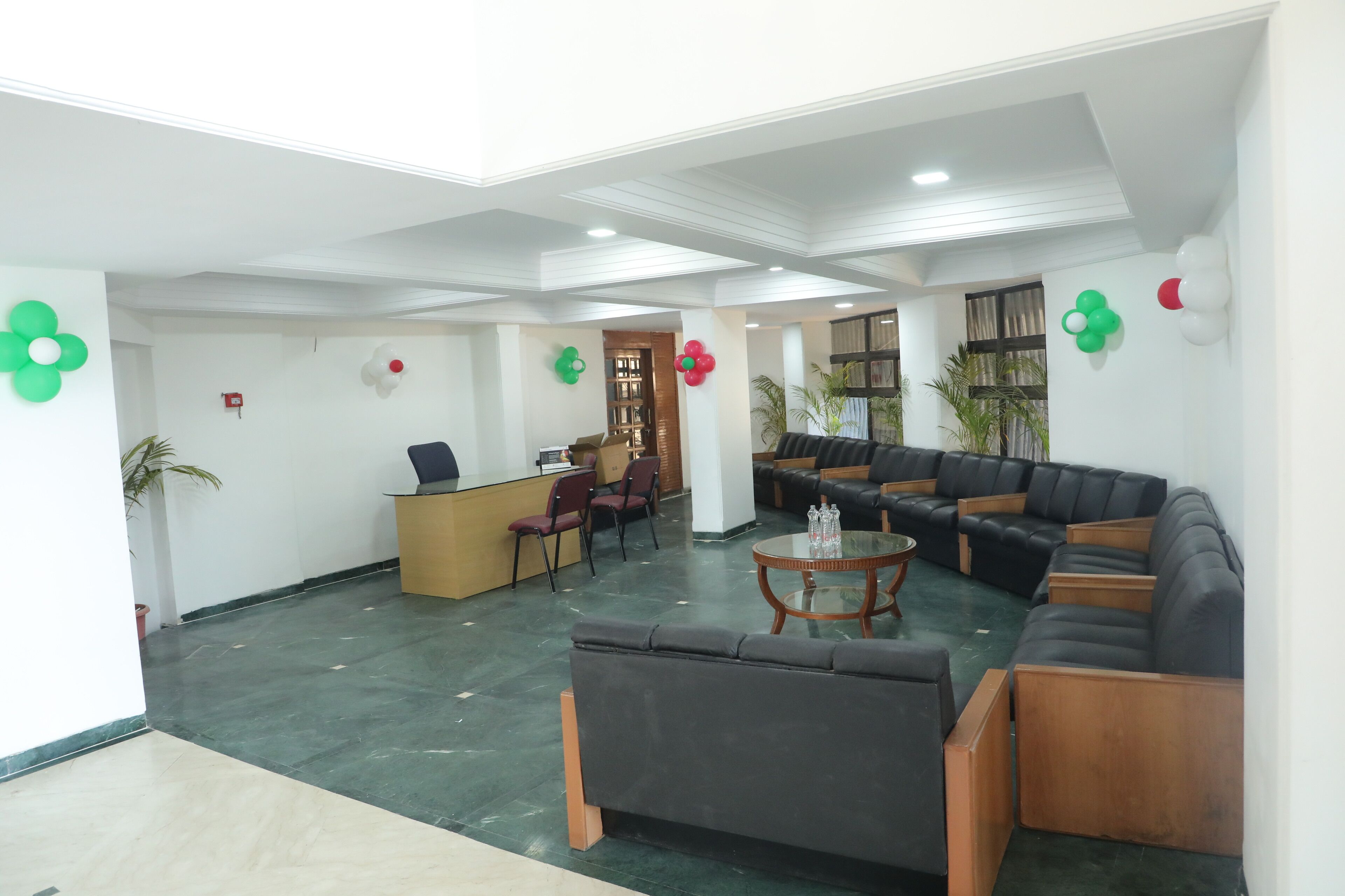 A spacious lobby with a reception desk, seating area, and decorative balloons.