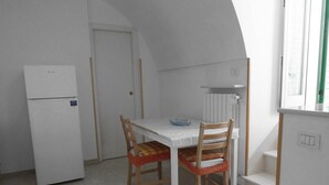 Eine kleine Küche mit einem weißen Kühlschrank, einem Tisch mit Stühlen und einem Fenster mit Blick.