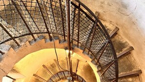 A spiral staircase with metal railings and a central light fixture.