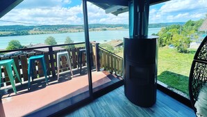 A balcony with a view of a lake, a chimney, and outdoor furniture.