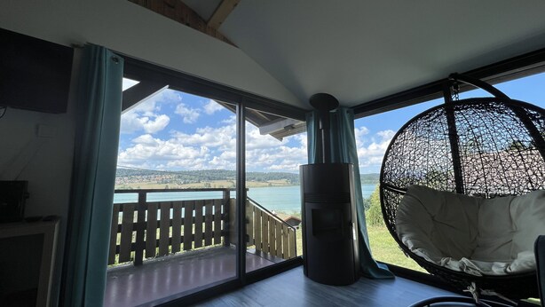 A room with a large window, a hanging chair, and a fireplace.