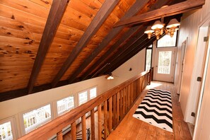 A wooden staircase with a black and white zigzag rug, wooden beams, and a ceiling fan. - Charming Waterfront House with Large Deck, Short Drive to North Conway (Madison)
