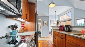 A modern kitchen with wooden cabinets, a stainless steel stove, and a large window providing natural light. - Rock Pond Condo 45 - Beautiful Ski in/Ski out condo unit on Saddleback! (Rangeley)