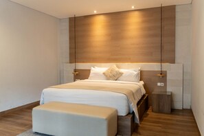 Une chambre à coucher moderne avec un grand lit, des tables de chevet et une tête de lit en bois.