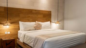 A bedroom with a wooden headboard, white bedding, and two pendant lights.