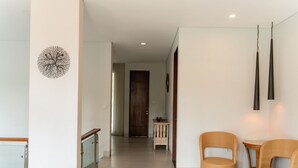 A hallway with a wooden door, a small table with a bowl, and two wicker chairs. - Atsuka Hill View 8BR Vila with Private Heated Pool (Cimenyan)