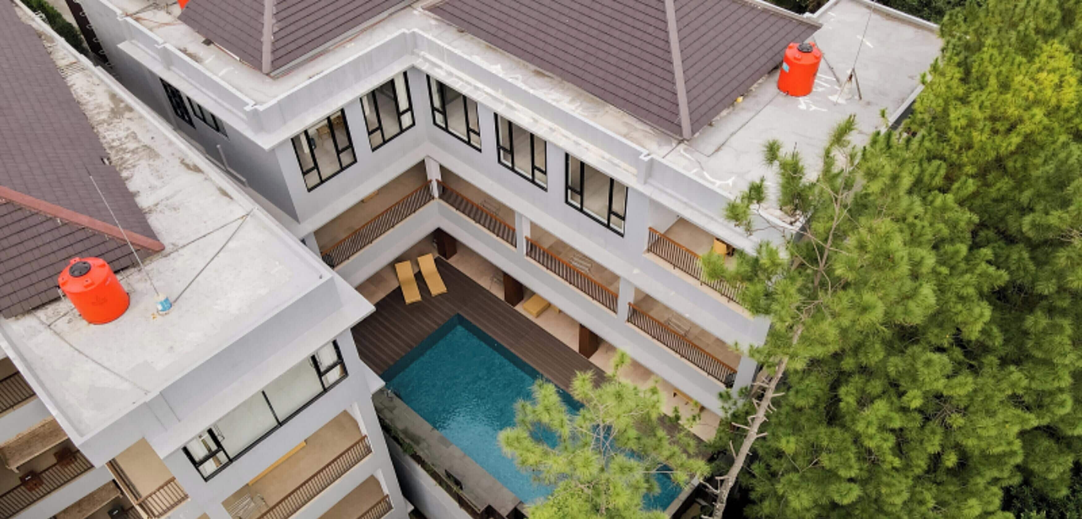 Un edificio residencial de varios pisos con un patio central que tiene una piscina, balcones y un hidrante rojo.