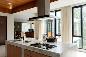 Uma cozinha moderna com uma ilha central, eletrodomésticos embutidos e grandes janelas.