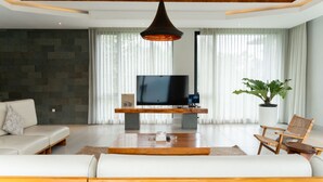 A modern living room with a flat-screen TV, a sofa, a coffee table, and a potted plant. - Atsuka Hill View 8BR Vila with Private Heated Pool (Cimenyan)