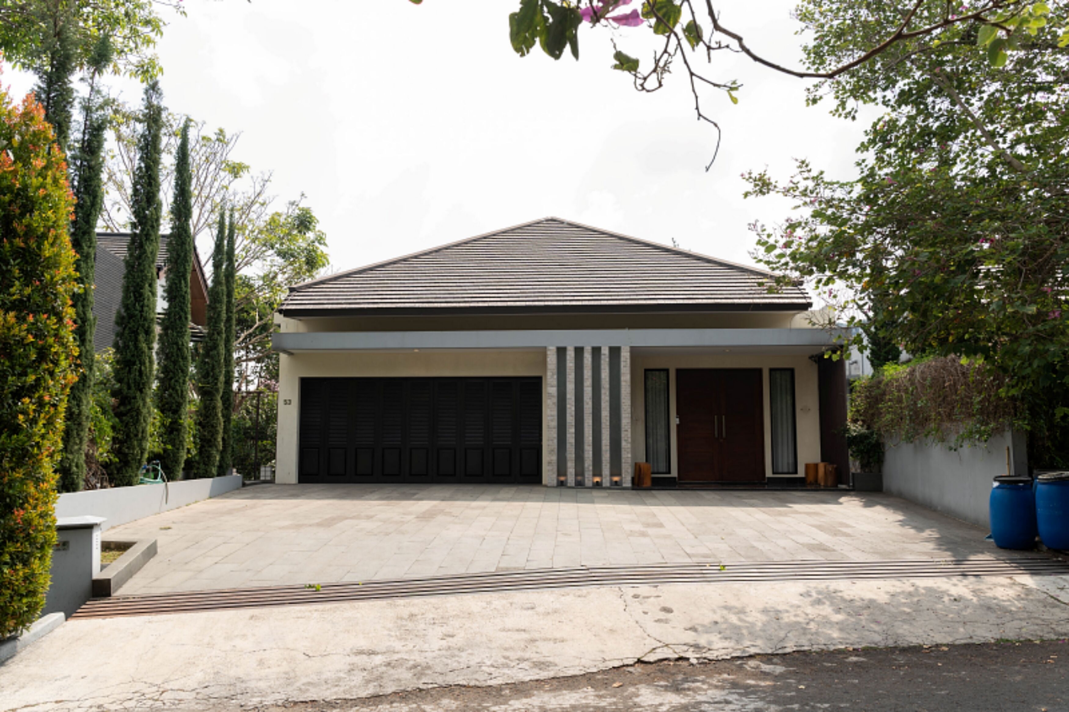 A modern two-story house with a garage, a driveway, and a landscaped garden.