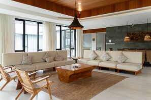 Een moderne woonkamer met een royale hoekbank, een houten salontafel en rieten stoelen.