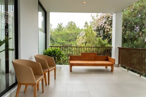 A balcony with a wooden bench and two wicker chairs, overlooking a garden with trees and shrubs. - Atsuka Hill View 8BR Vila with Private Heated Pool (Cimenyan)